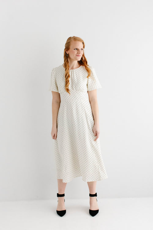Woman wearing a white dress with black polka dots on a white background